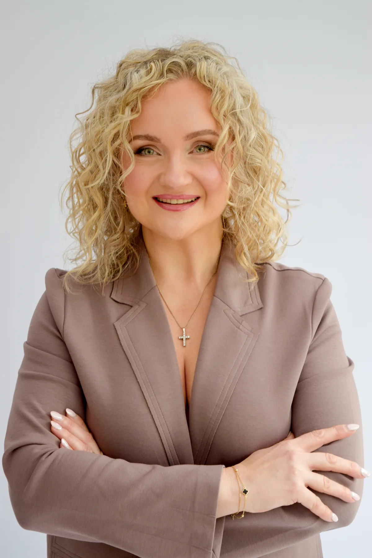 Anna Fullbrook smiling, with blonde curly hair, wearing a rose-brown blazer
