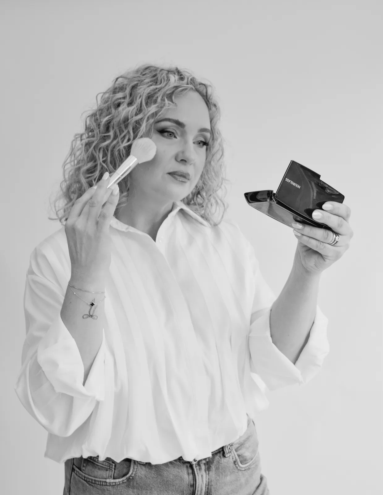 Black and white: Anna holding a brush and an open compact
