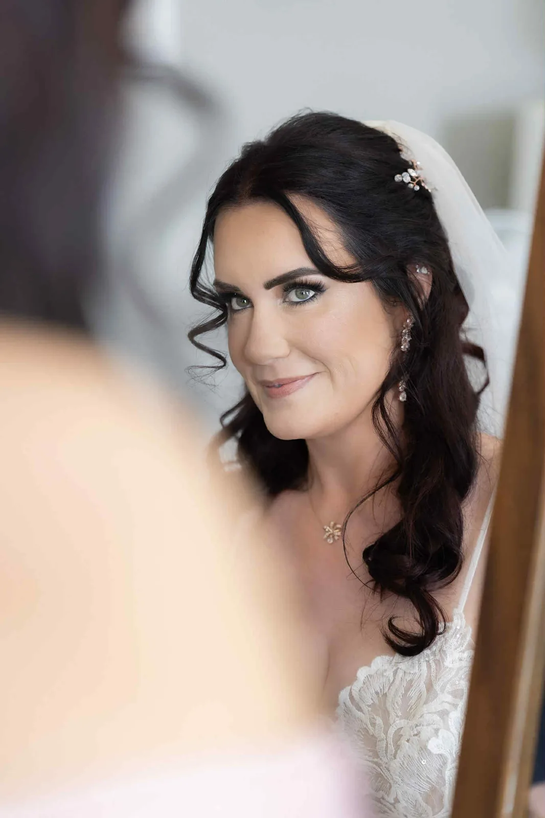 A bride with dark curls and a softly smoked eye, seen in a mirror