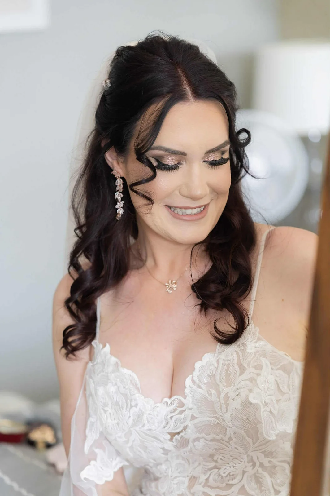 A bride in a lace gown with defined eyes and a soft rose lip