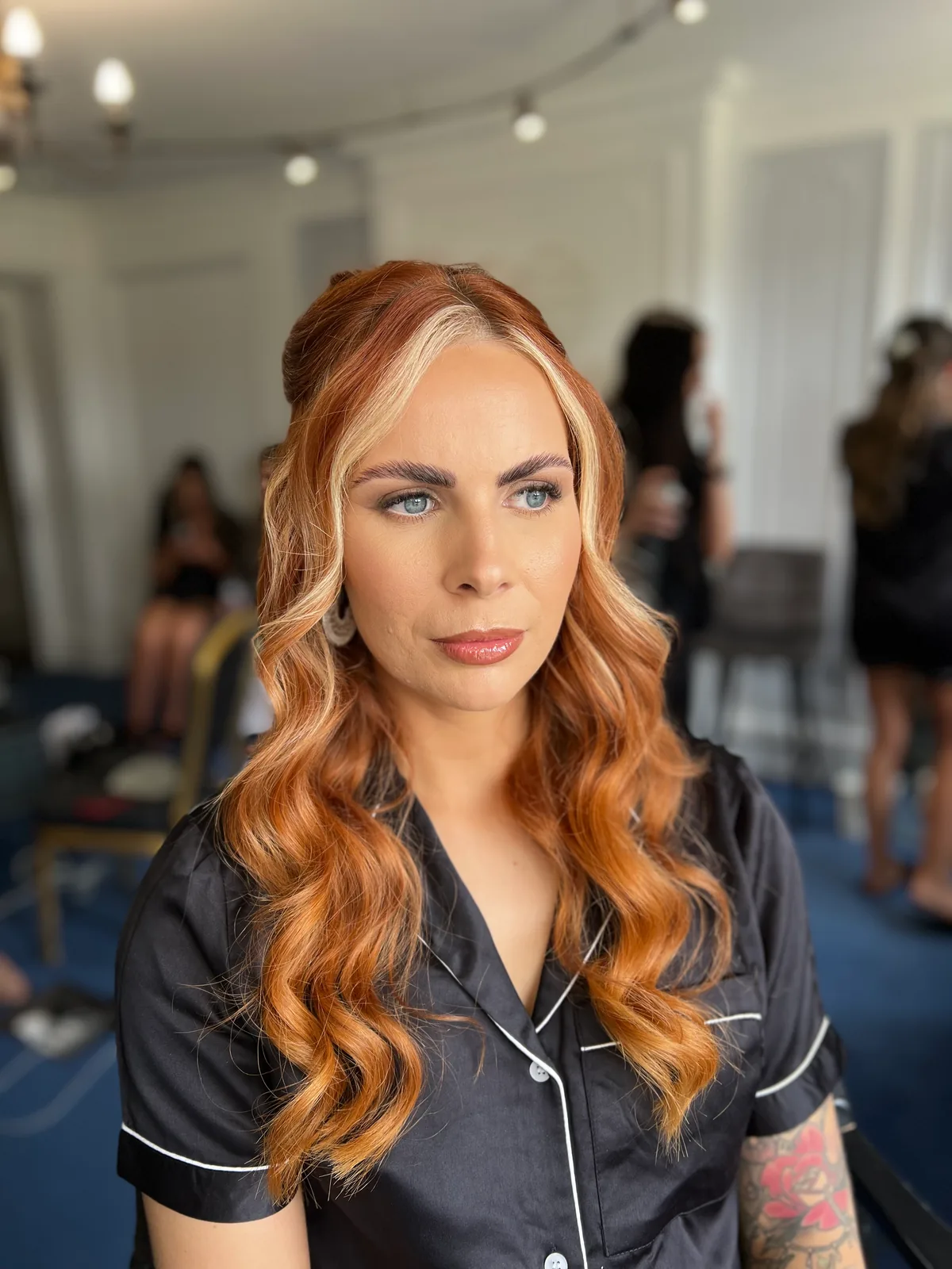 A member of the bridal party with long copper hair and sculpted makeup