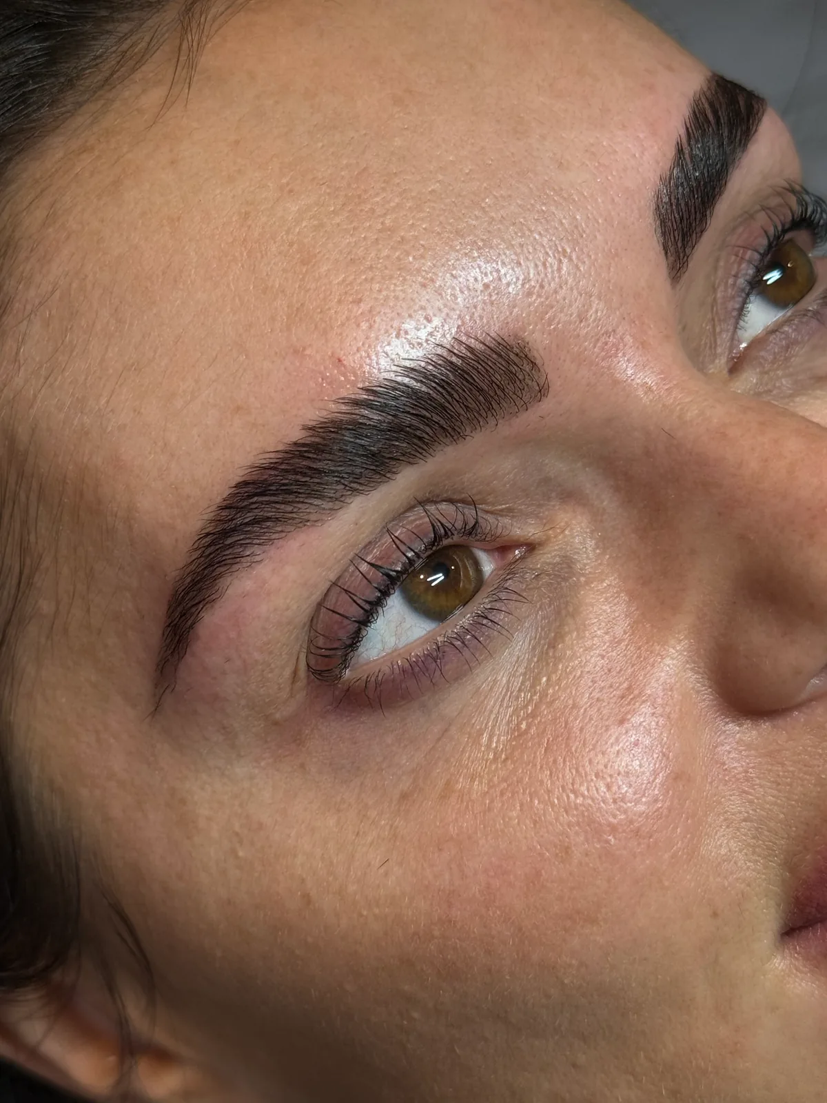 Close view of defined, tinted brows and lifted lashes