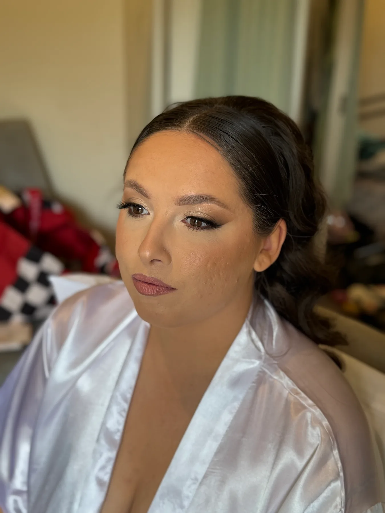 A client in a satin robe with sculpted, glowing makeup and defined lashes