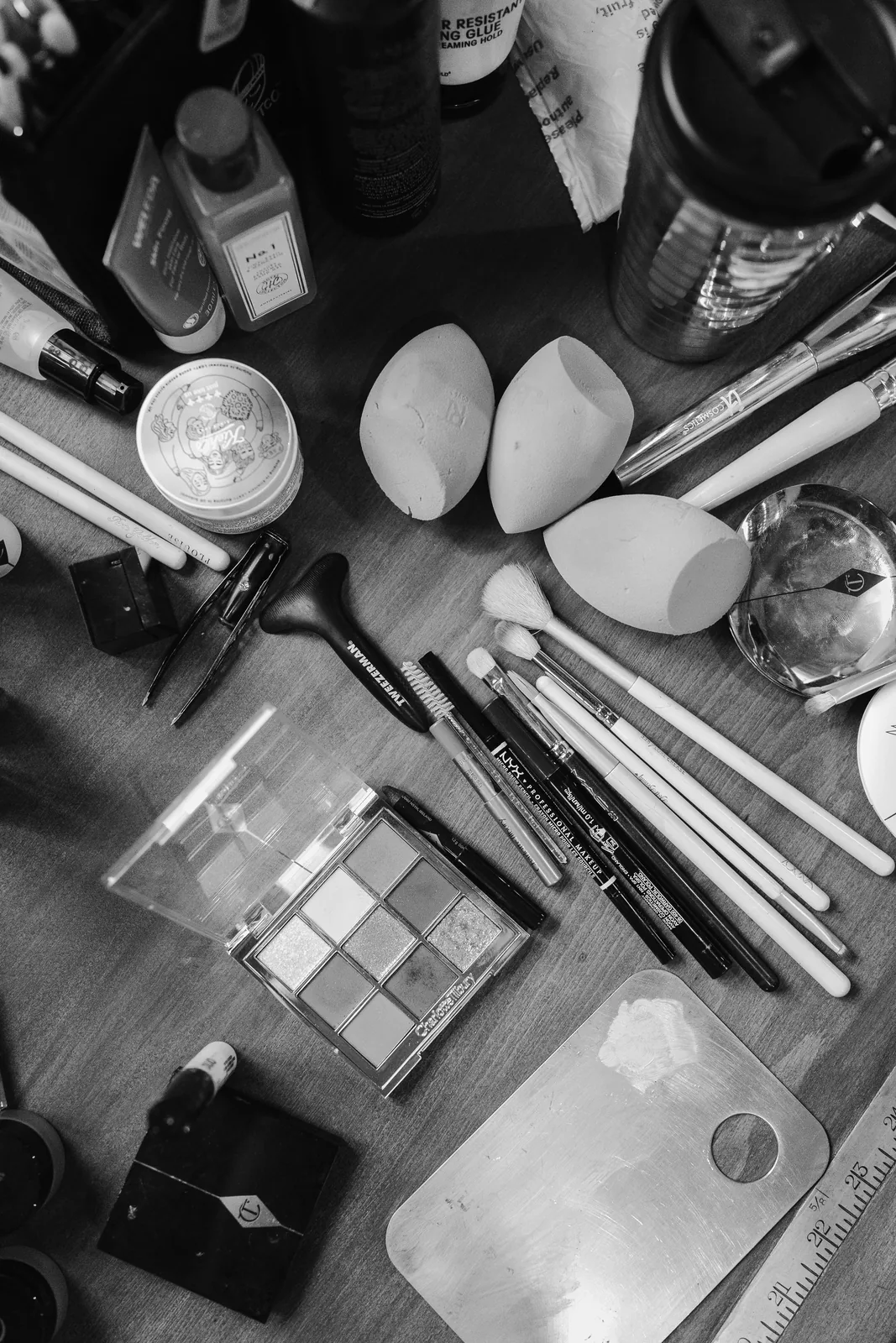Black and white flat lay of makeup brushes, sponges, palettes and skincare