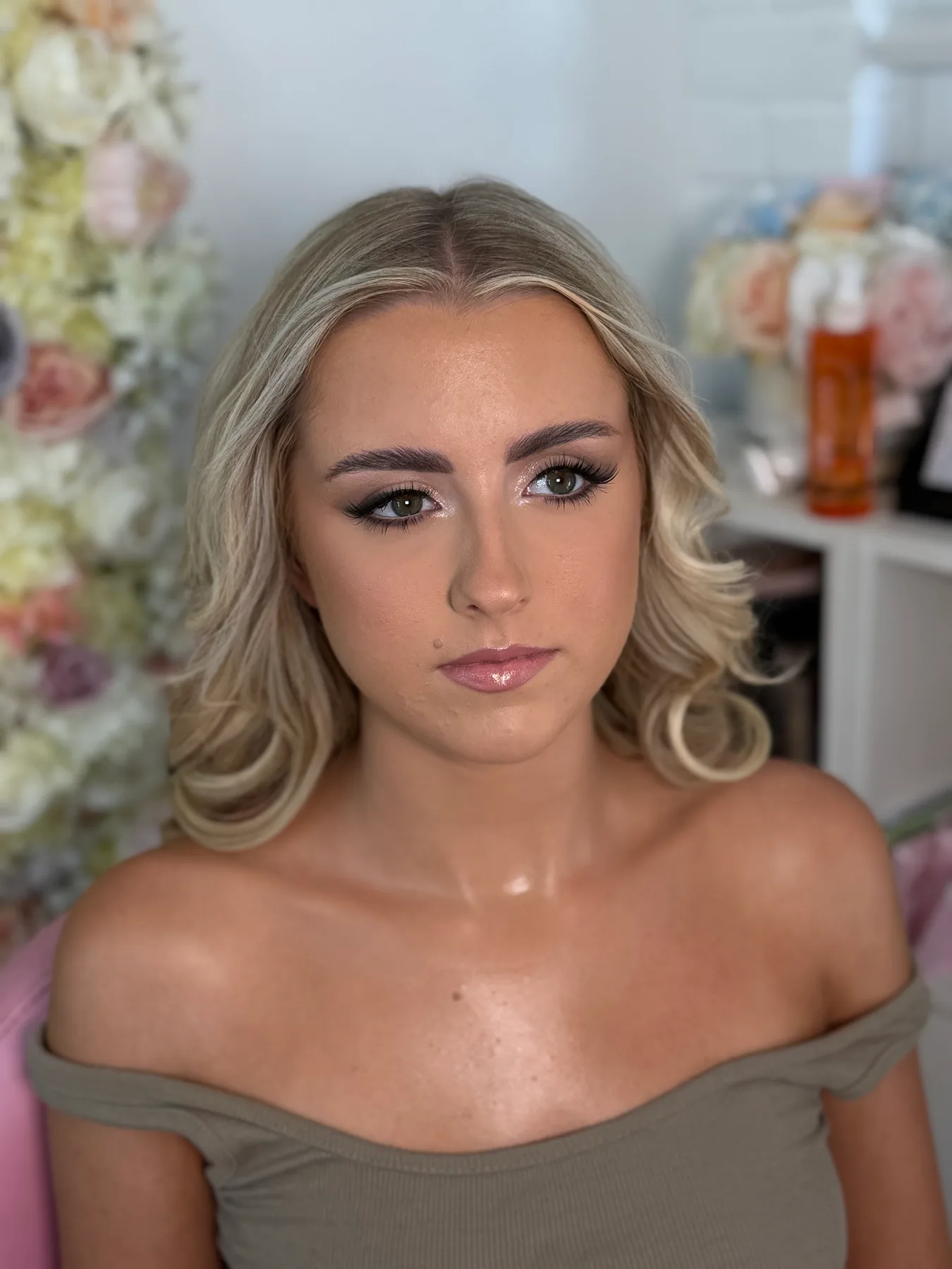 A young woman with softly sculpted prom makeup, defined lashes and a glossy nude lip
