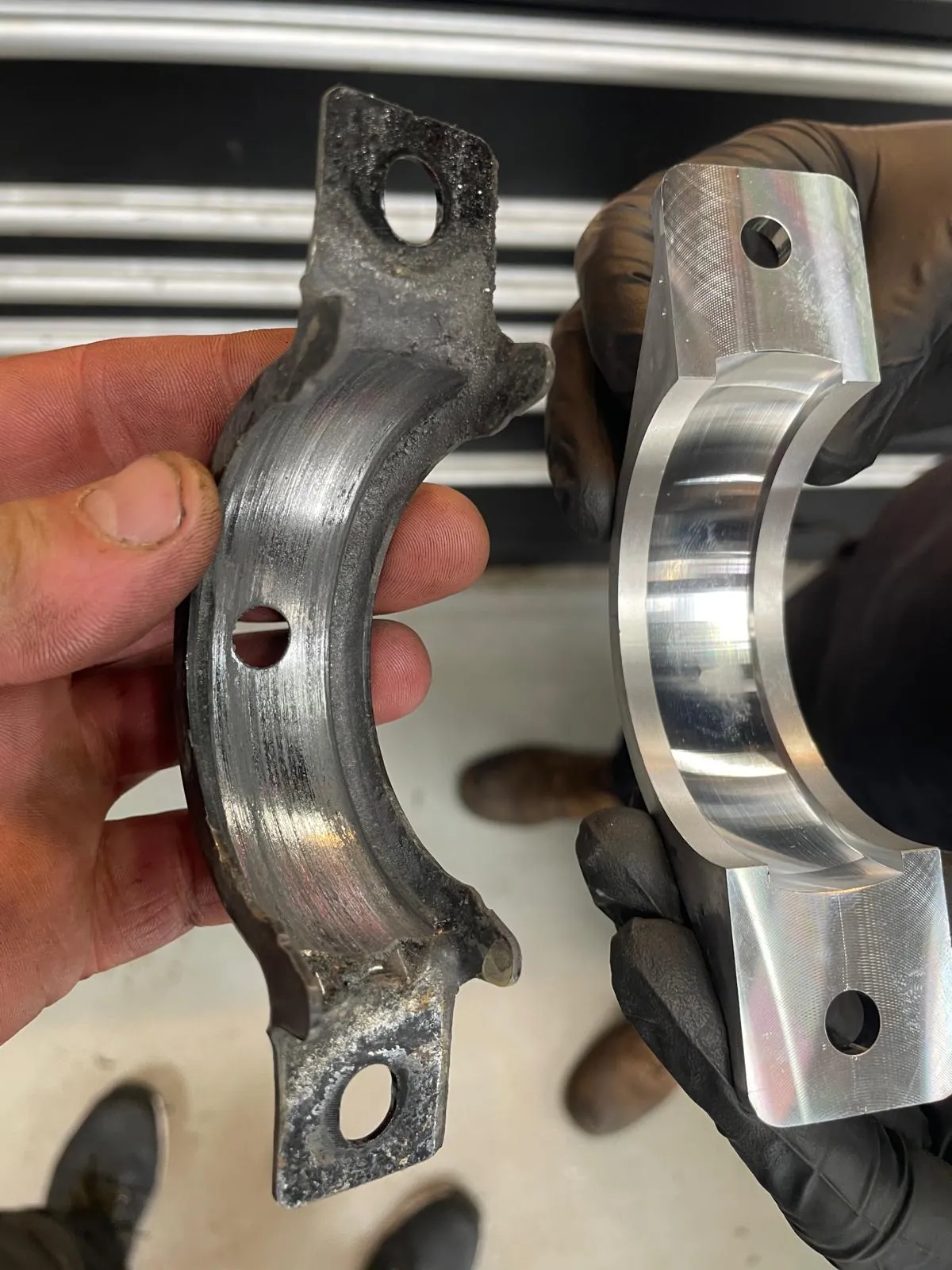 A worn bearing shell held beside its replacement