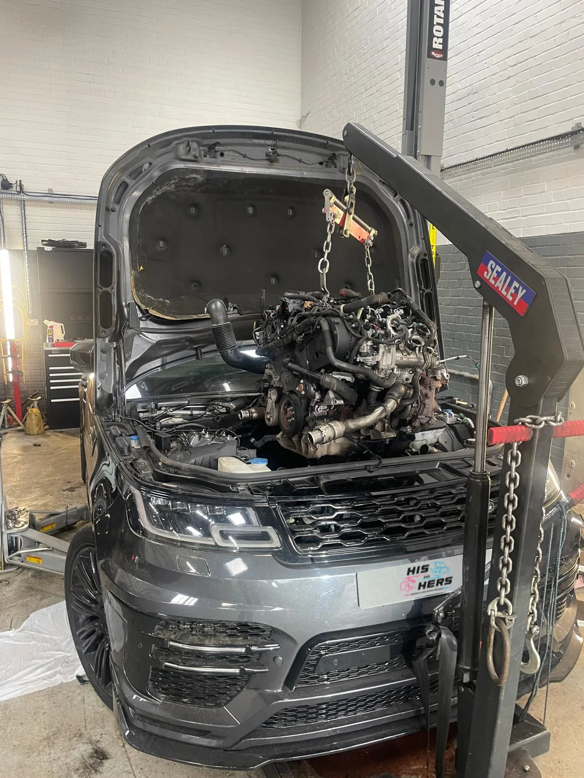 A Range Rover with its engine lifted by the workshop crane