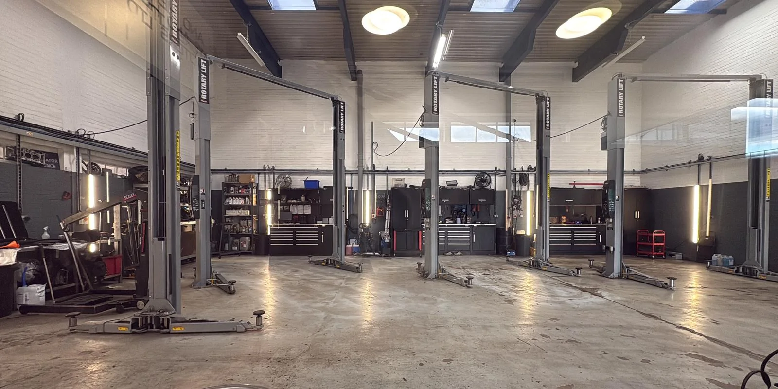 The bright His and Hers Motors workshop with four two-post lifts
