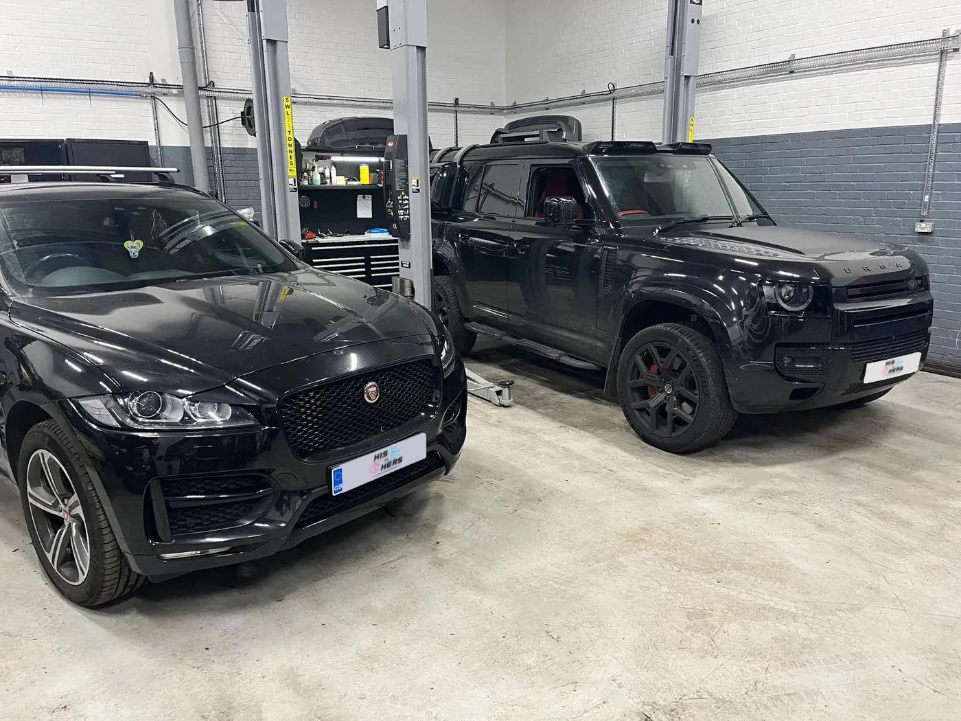 A Jaguar F-Pace and a Land Rover Defender in the His and Hers Motors service bays